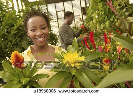 Stock Photograph - Couple choosing plants at nursery, (portrait). Fotosearch