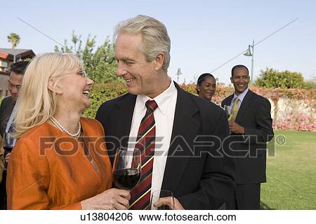 Stock Photograph - Couple drinking wine at outdoor party. Fotosearch