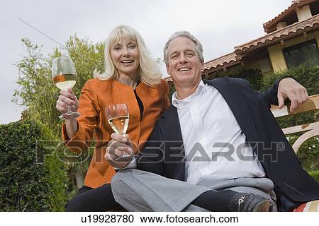 Stock Image - Couple drinking wine in garden, portrait. Fotosearch