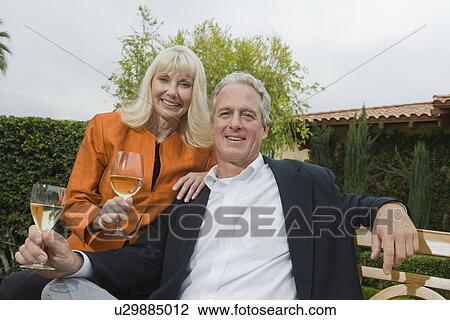 Stock Image - Couple drinking wine in garden, portrait. Fotosearch