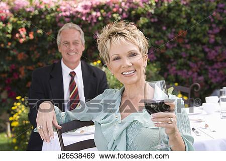 Stock Photo - Couple drinking wine outdoors, portrait. Fotosearch
