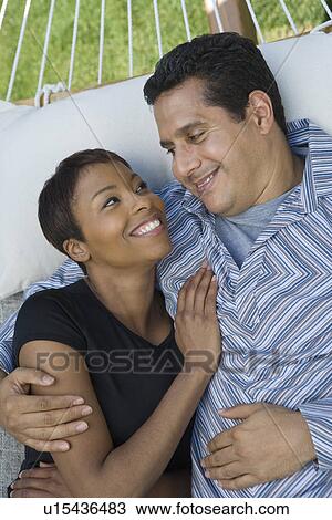 Stock Image - Couple embracing in hammock. Fotosearch