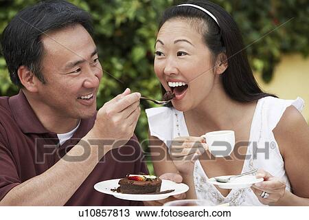 Stock Image - Couple having coffee and cake in garden. Fotosearch