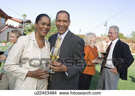 Picture - Couple holding drinks at outdoor party, portrait. Fotosearch