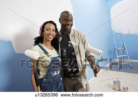 Stock Photograph - Couple holding paint rollers, portrait, elevated view. Fotosearch