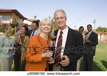 Stock Photography - Couple holding wine at outdoor party, portrait. Fotosearch
