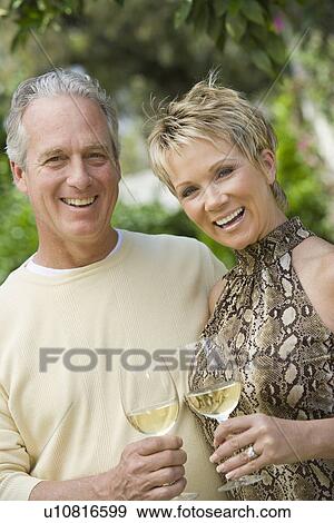Couple holding wine outdoors, portrait View Large Photo Image Stock Photo - Couple holding wine outdoors, portrait. Fotosearch
