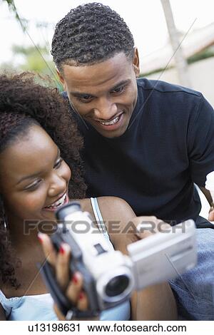 Stock Image - Couple looking at camcorder's screen. Fotosearch