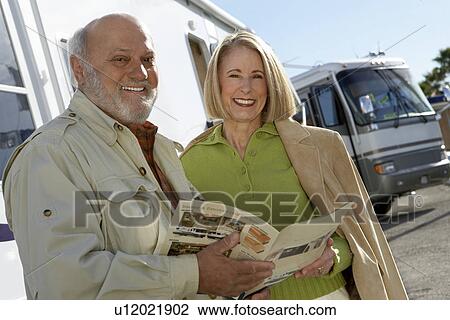 Stock Image - Couple looking through RV brochure, portrait. Fotosearch