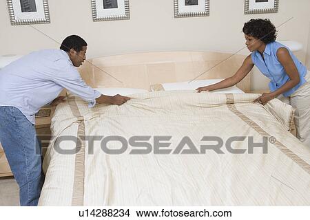 Picture - Couple making a bed together. Fotosearch