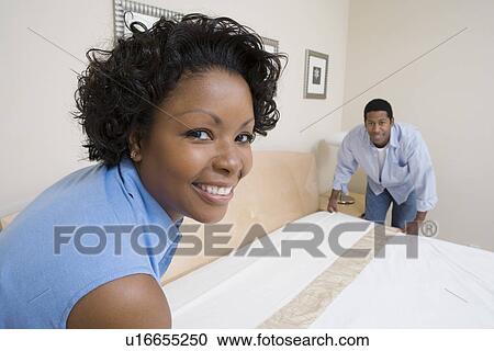 Stock Image - Couple making a bed together. Fotosearch