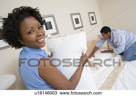 Stock Image - Couple making a bed together. Fotosearch