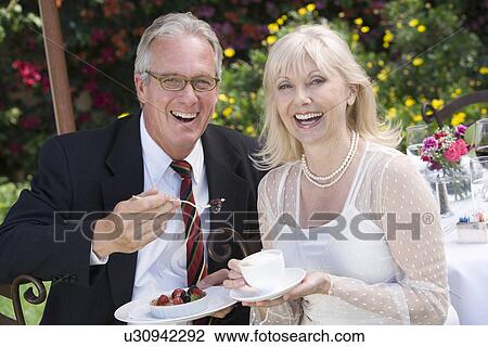 Stock Image - Couple relaxing at outdoor table, portrait. Fotosearch
