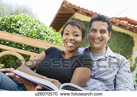 Stock Image - Couple relaxing in back yard, portrait. Fotosearch