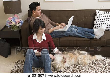 Stock Image - Couple relaxing in living room. Fotosearch