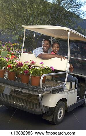 Couple riding in cart at plant nursery View Large Photo Image Stock Image - Couple riding in cart at plant nursery. Fotosearch