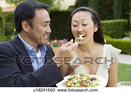 Stock Image - Couple sharing dessert outdoors. Fotosearch