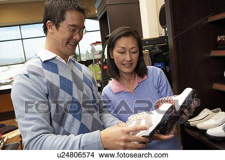 Picture - Couple shopping, looking at golf shoes in Golf Shop. Fotosearch