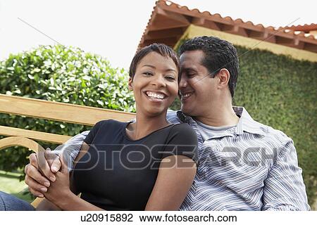 Stock Image - Couple Sitting on Bench in Garden. Fotosearch