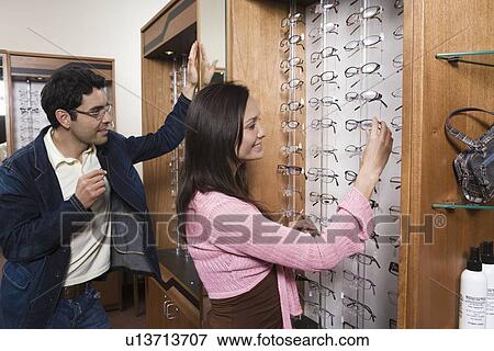 Stock Photo - Couple trying on eyeglasses in store. Fotosearch
