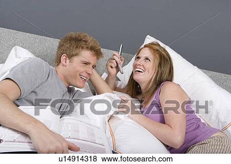 Stock Photo - Couple Using Cell Phone Together Bedroom. Fotosearch