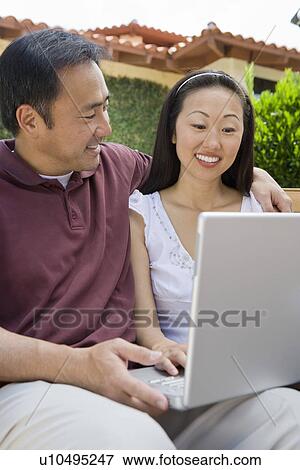 Couple using laptop in back yard View Large Photo Image Stock Photo - Couple using laptop in back yard. Fotosearch