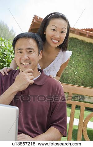 Stock Photo - Couple using laptop in back yard, portrait. Fotosearch