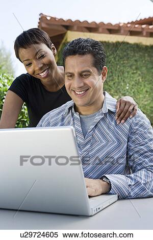 Stock Photography - Couple using laptop in back yard. Fotosearch