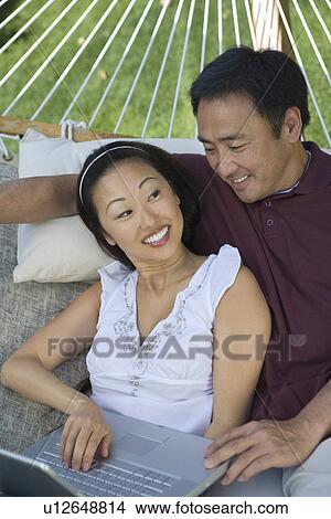 Picture - Couple using laptop in hammock. Fotosearch