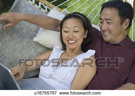 Stock Photo - Couple using laptop in hammock. Fotosearch