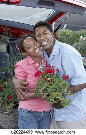 Couple with plant by car, (portrait) View Large Photo Image Stock Photo - Couple with plant by car, (portrait). Fotosearch
