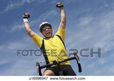 Cyclist riding bicycle and cheering, portrait, low angle view View Large Photo Image Stock Photo - Cyclist riding bicycle and cheering, portrait, low angle view. Fotosearch