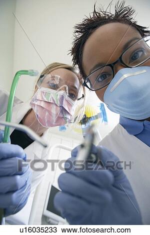 Stock Image - Dentist and hygienist in surgery, (close-up). Fotosearch