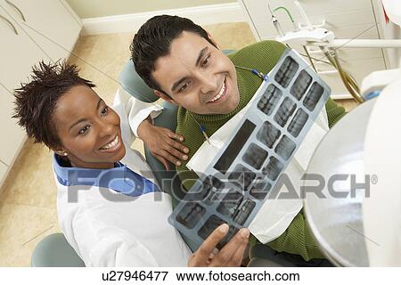 Dentist and patient examining X-ray in surgery View Large Photo Image Stock Photo - Dentist and patient examining X-ray in surgery. Fotosearch