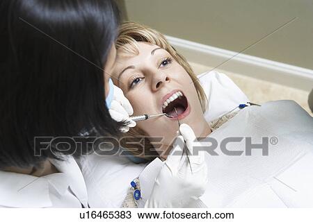 Dentist examining female patient in surgery View Large Photo Image Stock Image - Dentist examining female patient in surgery. Fotosearch