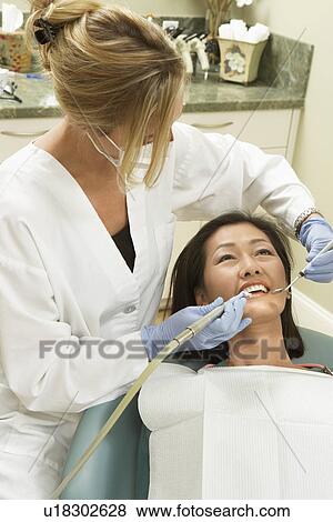 Dentist examining female patient in surgery View Large Photo Image Stock Photo - Dentist examining female patient in surgery. Fotosearch