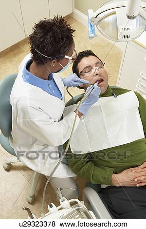 Stock Photo - Dentist examining male patient. Fotosearch