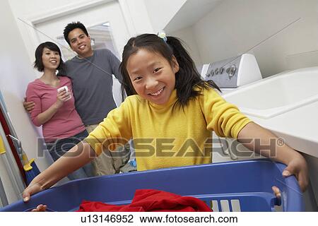 Stock Image - Family with daughter (7-9) doing laundry, portrait. Fotosearch