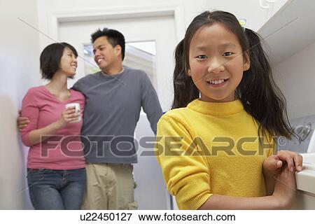 Stock Photo - Family with daughter (7-9) in laundry room. Fotosearch