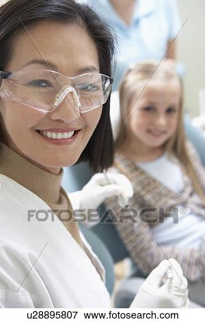 Stock Photo - Female dentist with girl in surgery, (portrait). Fotosearch
