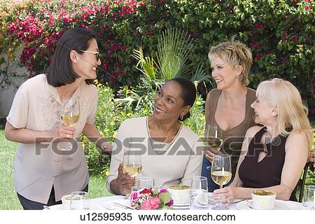 Stock Photography - Female friends drinking wine at outdoor table. Fotosearch