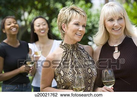 Stock Image - Female friends drinking wine outdoors. Fotosearch