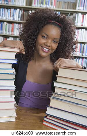 Female student in college library, with stacks of books View Large Photo Image Stock Photo - Female student in college library, with stacks of books. Fotosearch