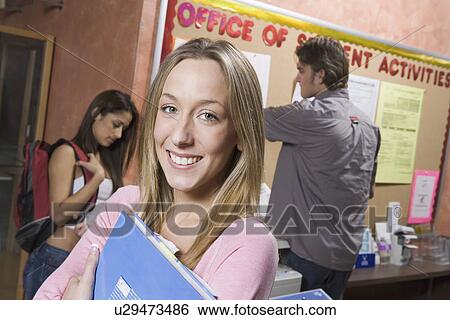 Female student in college office, clutching folder View Large Photo Image Stock Photograph - Female student in college office, clutching folder. Fotosearch