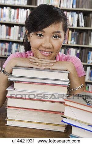 Female student leaning on stack of books in library View Large Photo Image Stock Image - Female student leaning on stack of books in library. Fotosearch