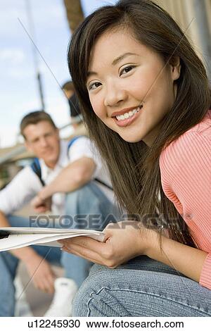 Stock Image - Female student relaxing on campus, (portrait). Fotosearch