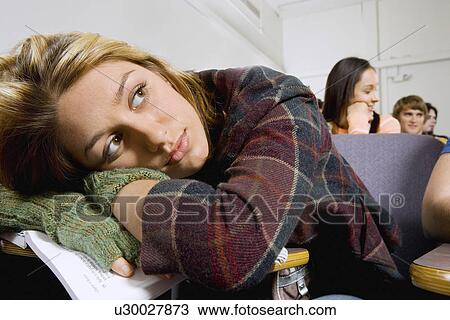 Female student resting on textbook during class View Large Photo Image Stock Image - Female student resting on textbook during class. Fotosearch
