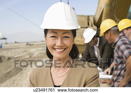 Stock Image - Female surveyor and construction workers on site, portrait. Fotosearch