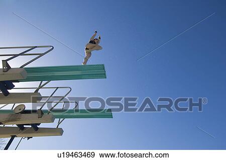 Stock Photo - Female swimmer preparing to dive from diving board. Fotosearch