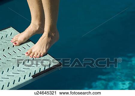 Stock Image - Female swimmer standing on diving board. Fotosearch